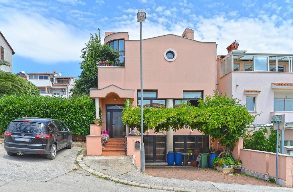 a car parked in front of a pink house at Apartments Marijan 105 in Pula