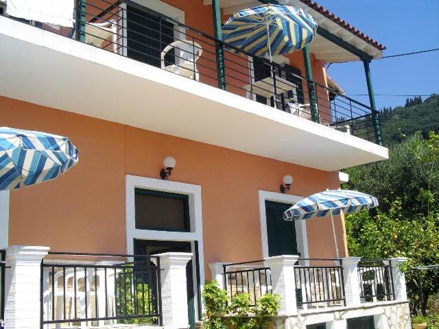 een huis met 2 parasols op een balkon bij Nikolas Apartments Yianna, Kalami bay sea view in Kalámi