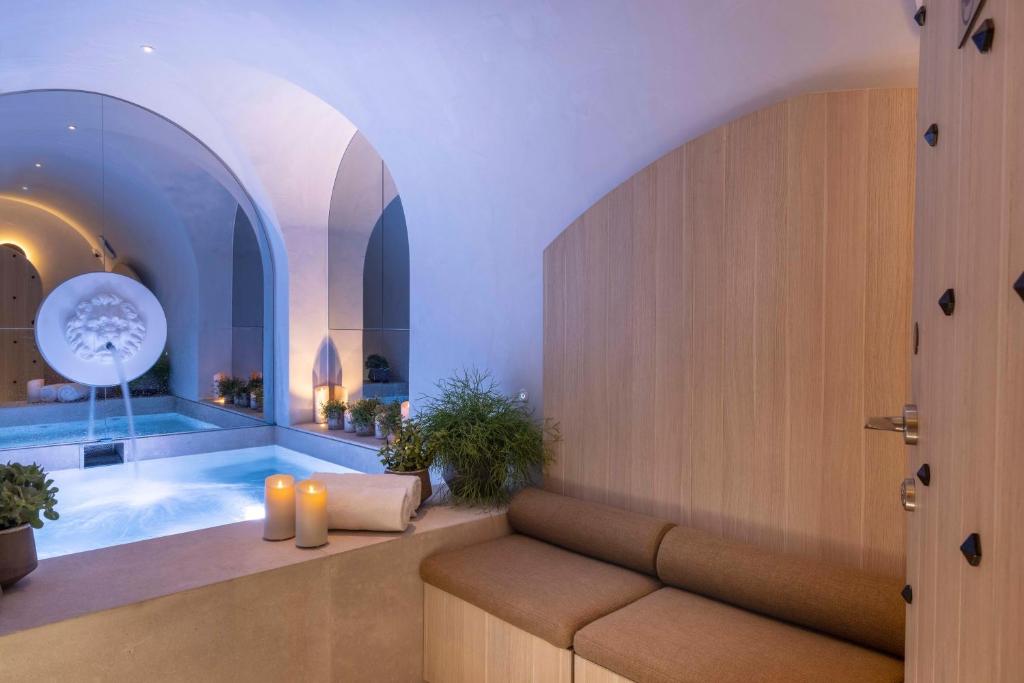 a room with a tub with a couch and candles at Hôtel Vinci Due & Spa in Paris