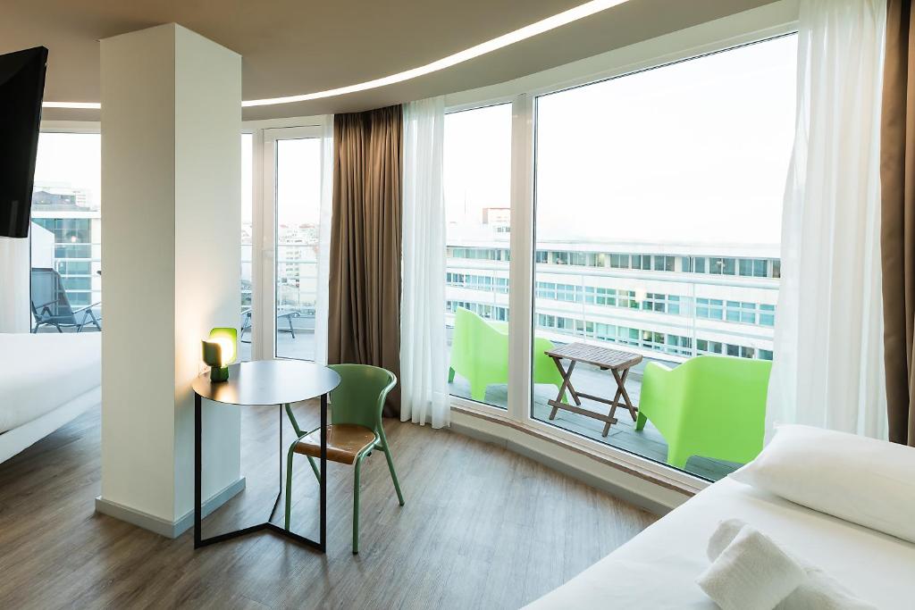 A bright bedroom with a large glazed corner, small desk, and balcony seating.