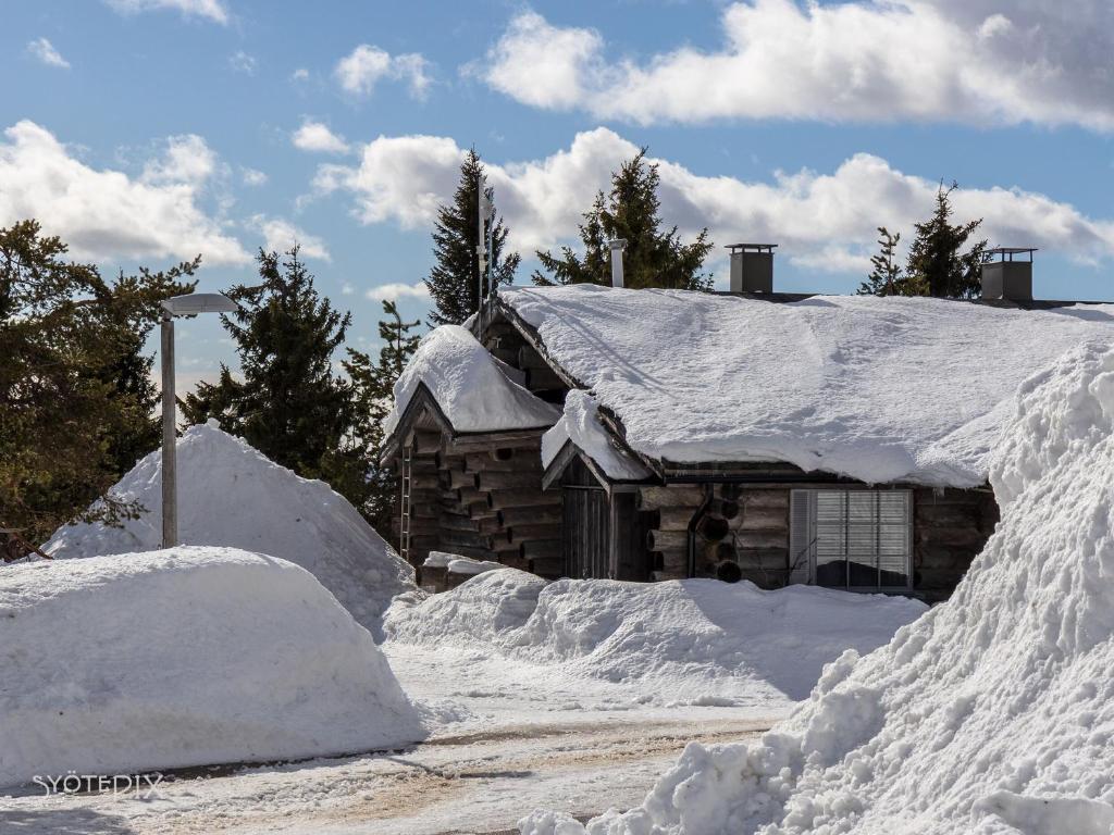 una baita di tronchi ricoperta di neve accanto a una strada di Revontuli 6 a Syöte