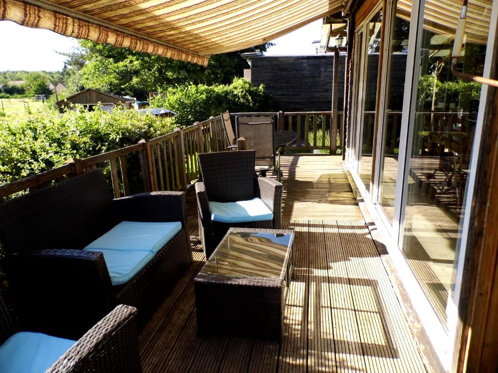 a porch with couches and chairs and a table at Le petit Marais n° 2 in Nouan-le-Fuzelier