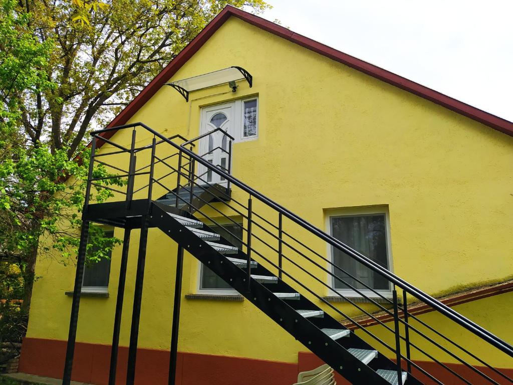 a yellow house with a staircase leading to a window at Twins House - Dorka Apartman in Bogács