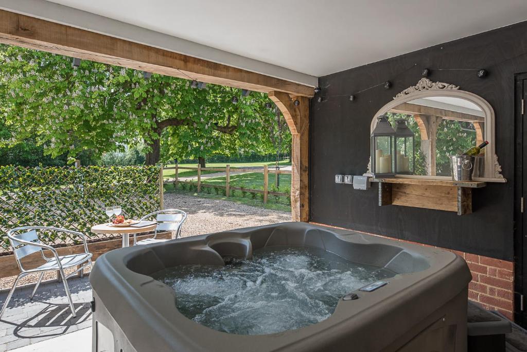 bañera grande en una habitación con patio en Geoff's Rest at Pond Hall Farm in Hadleigh with Private Hot Tub, en Ipswich