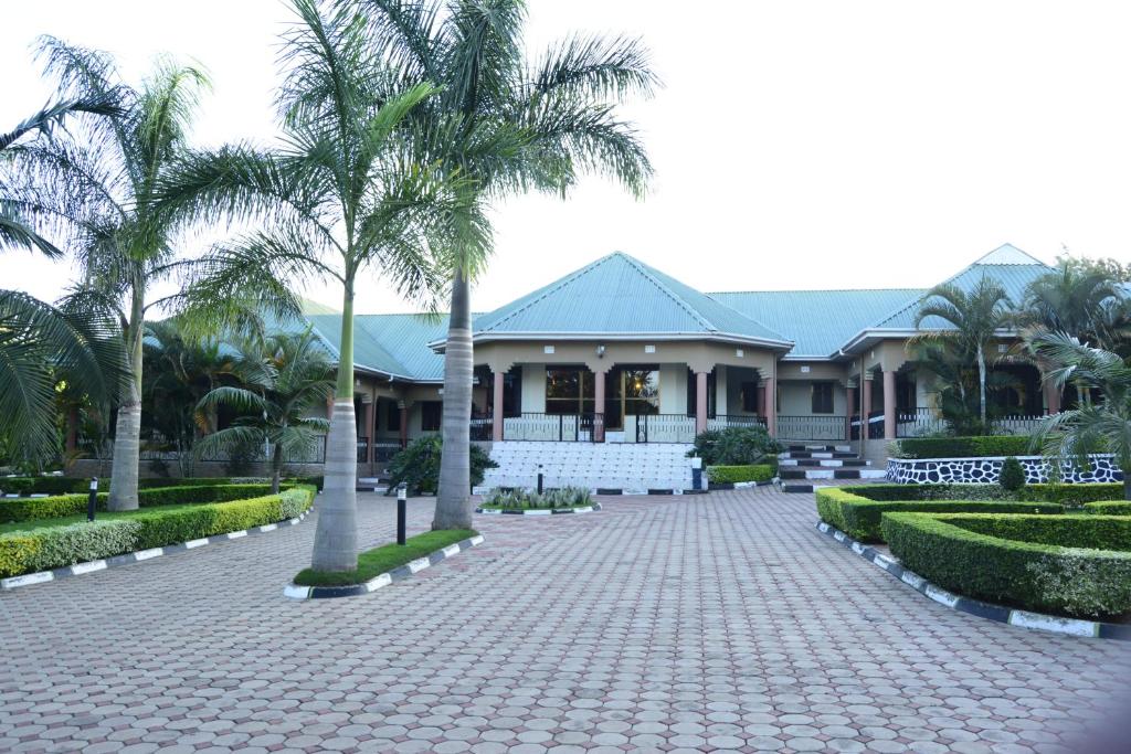 a house with palm trees in front of a driveway at Africa Lodge Arusha in Nkoaranga