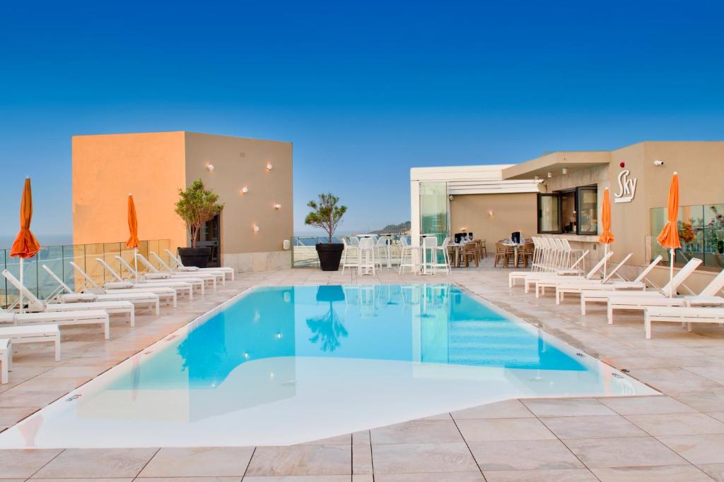 una piscina con sillas y un restaurante en Luna Holiday Complex, en Mellieħa