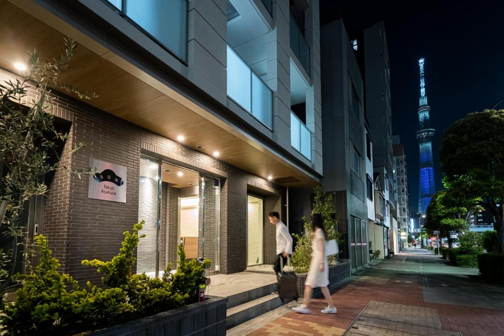 un hombre y una mujer caminando por una acera en frente de un edificio en BON Tokyo Asakusa, en Tokio