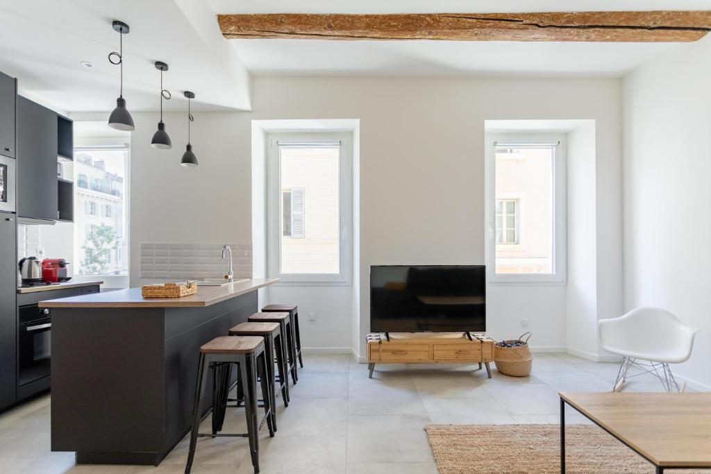 une cuisine avec un îlot noir et des tabourets dans l'établissement LES PIEDS DANS LE VIEUX PORT, à Marseille