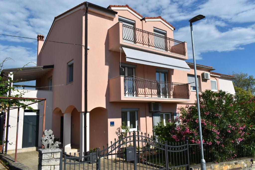 un edificio rosa con balcones y una valla en Studio Max with parking, en Rovinj