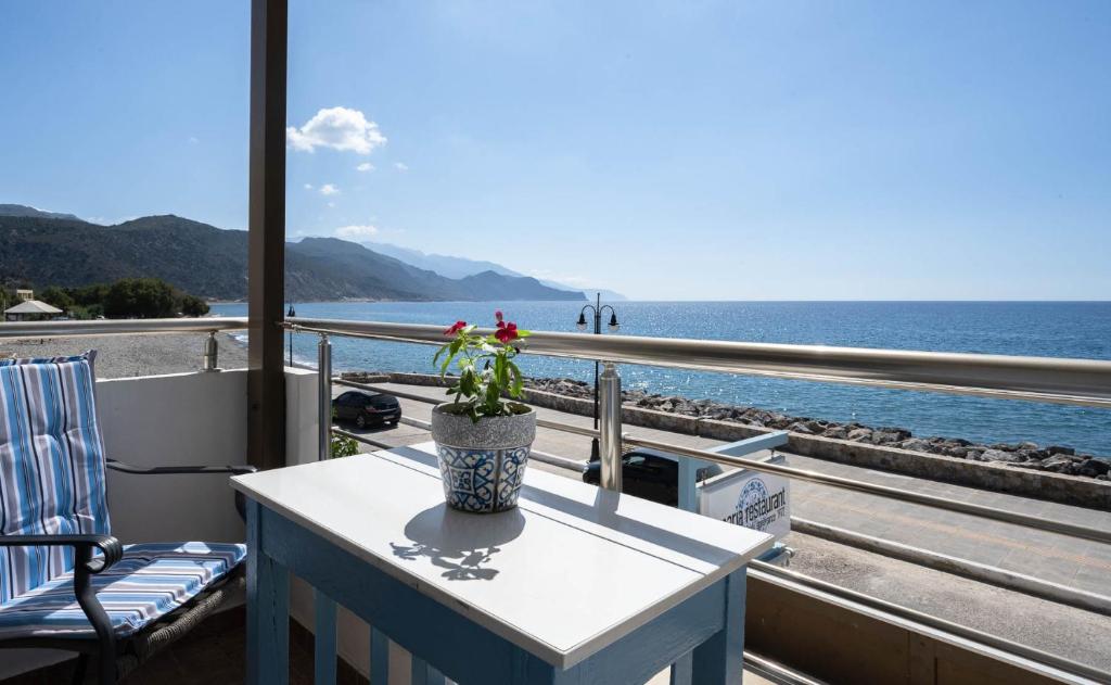 una mesa con una maceta en un balcón con vistas al océano en Maria's Hotel, en Palaiochóra