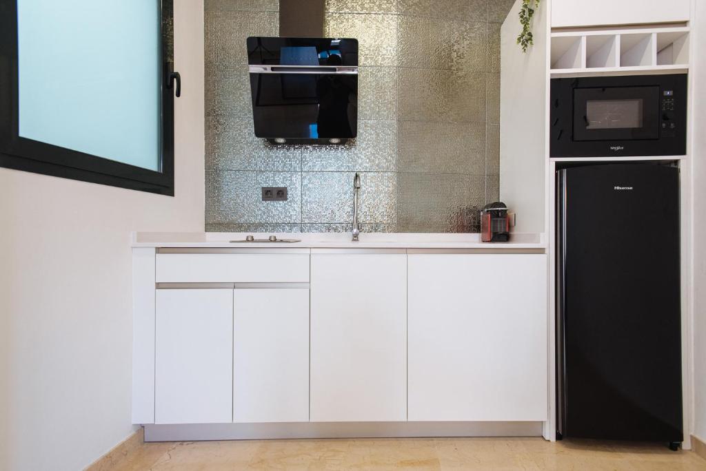 kuchnia z białymi szafkami i czarną lodówką w obiekcie Guardamino Dúplex Suite Apartment w Sewilli