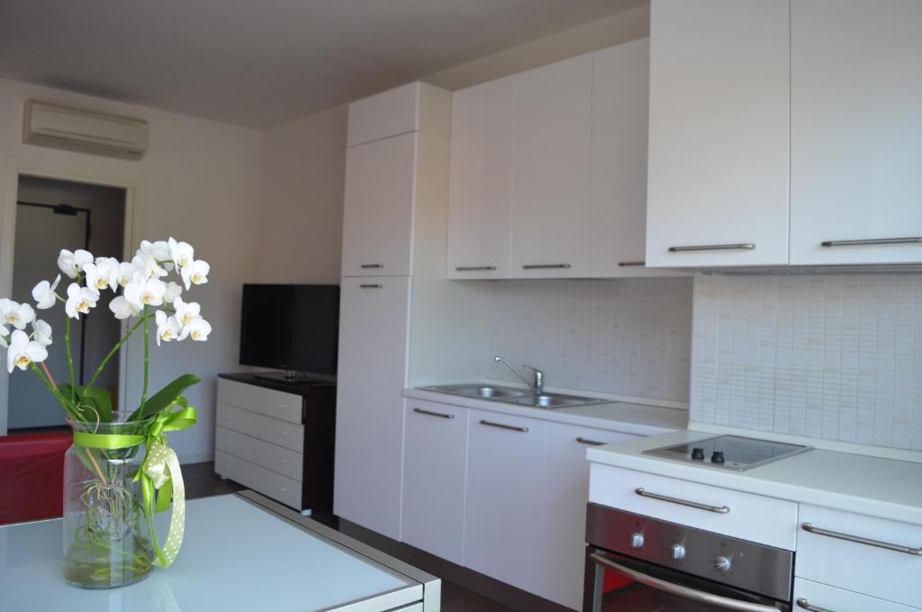 a white kitchen with a vase of flowers on a table at Residence Empire in Cattolica