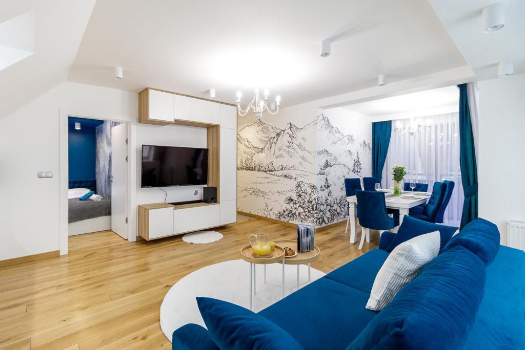ein Wohnzimmer mit einem blauen Sofa und einem Tisch in der Unterkunft Bogdańskiego Residence in Zakopane