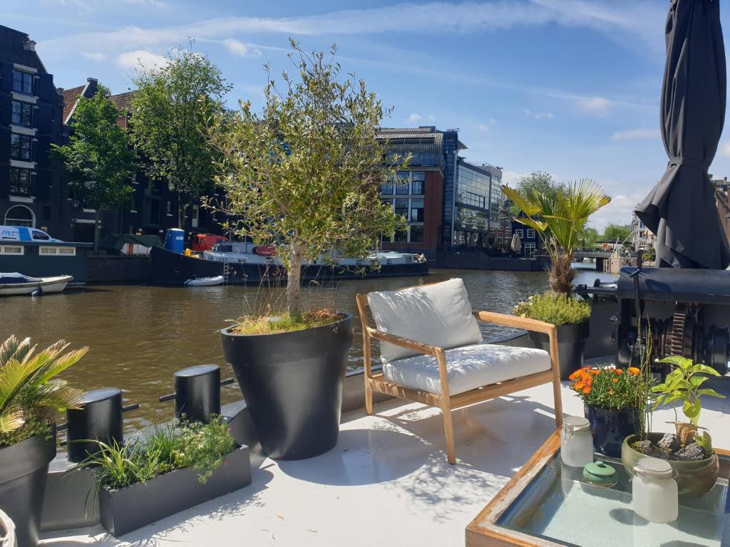 una silla sentada en un balcón con macetas en Luxurious 110m² 3br Houseboat in Amsterdam Centre!, en Ámsterdam
