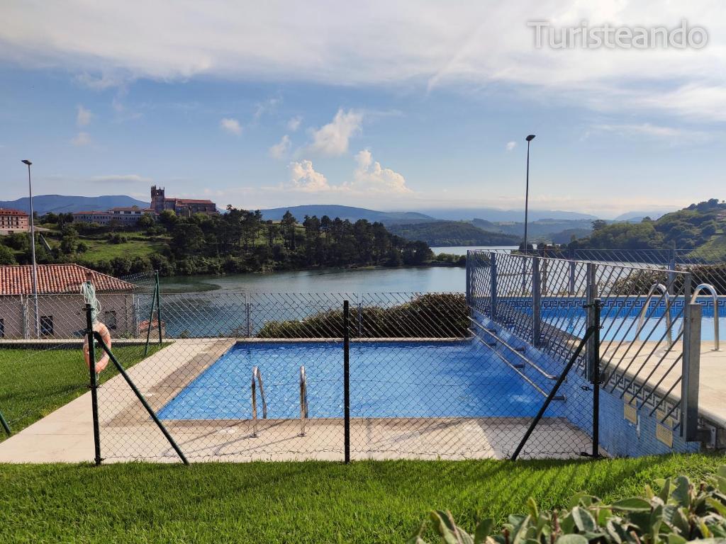 a large swimming pool next to a body of water at Dúplex Marisma de Pombo - Parking privado y vistas inolvidables in San Vicente de la Barquera