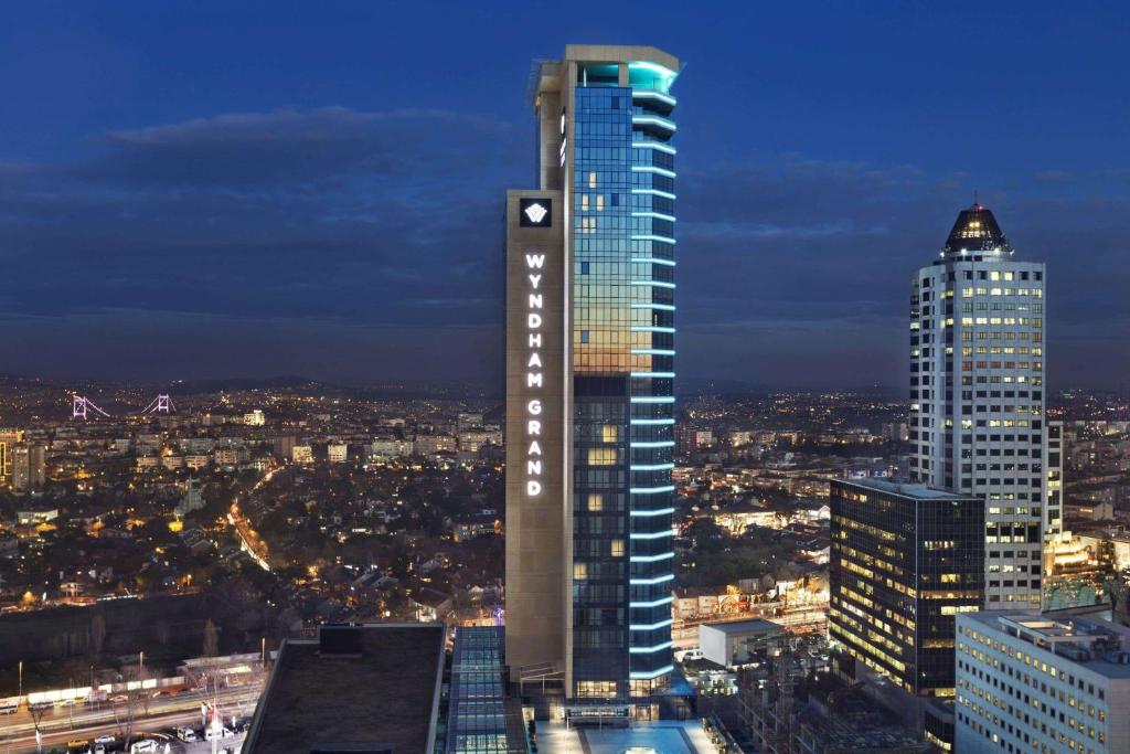 een hoog gebouw in een stad 's nachts bij Wyndham Grand Istanbul Levent in Istanbul