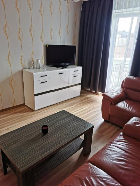 ein Wohnzimmer mit einem TV und einem Couchtisch in der Unterkunft Laisvės 10 in Telšiai