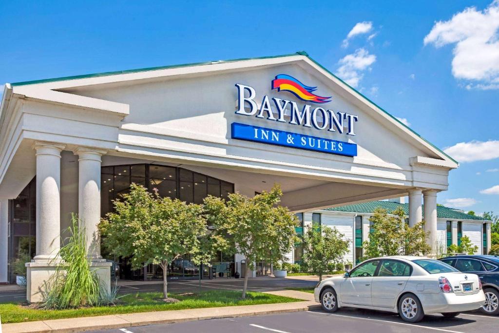a baysworth inn and suites building with a car parked in front at Baymont by Wyndham Louisville Airport South in Louisville