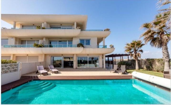 a building with a swimming pool in front of a house at VILLA BLANCA, La MANGA, POOL& SEA San Javier, Murcia in La Manga del Mar Menor