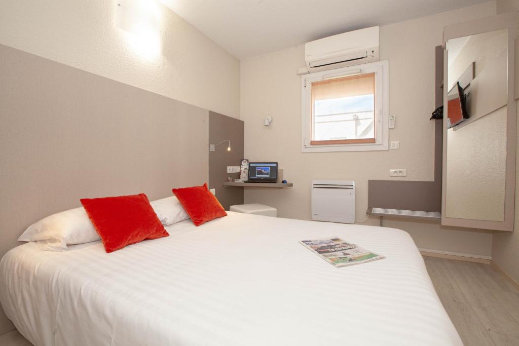 a bedroom with a large white bed with red pillows at Best Hotel Lyon - Saint Priest in Saint-Priest