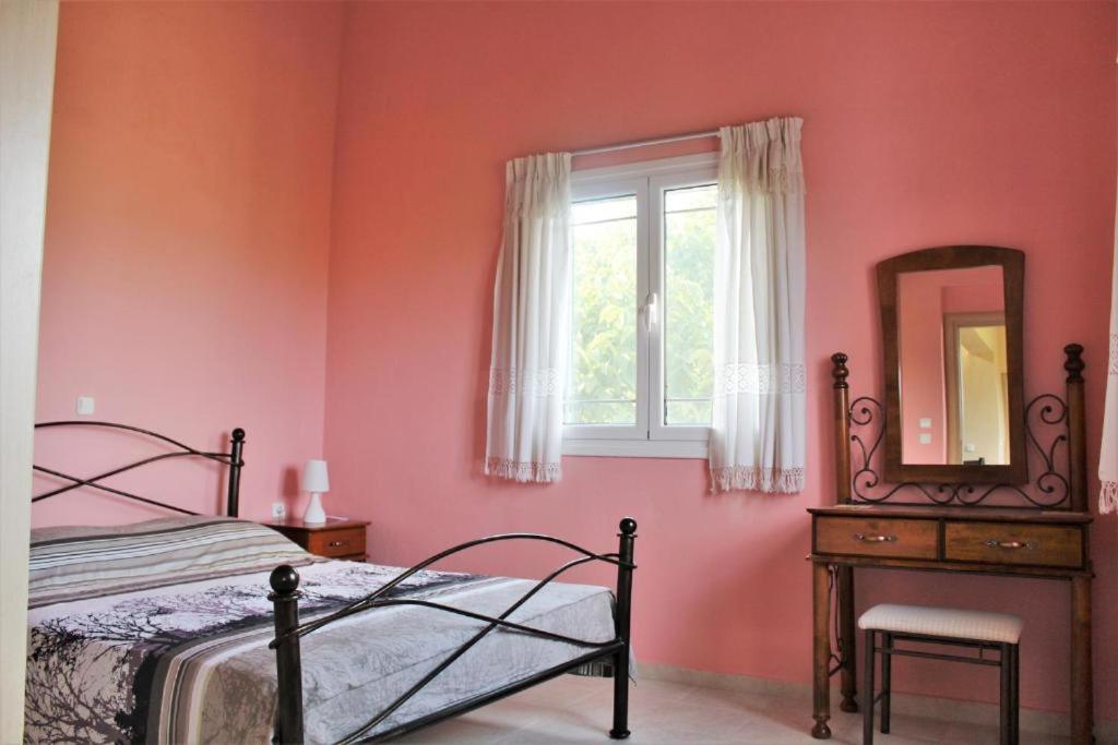 een slaapkamer met een bed, een spiegel en een raam bij Zeus and Hera Apartments in Nikiana