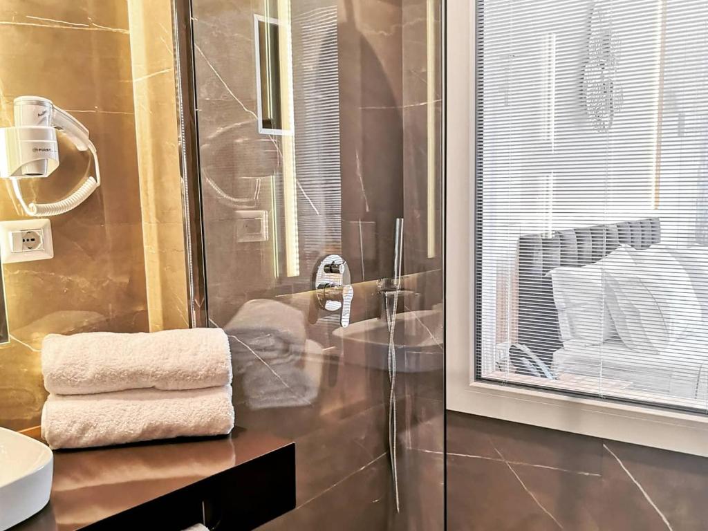 a bathroom with a shower and a sink and towels at Iliad Hotel in Durrës