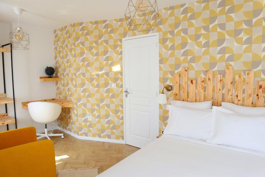 - une chambre avec un lit blanc et un mur jaune dans l'établissement Villa Noellet - Clermont Ferrand, à Aubière
