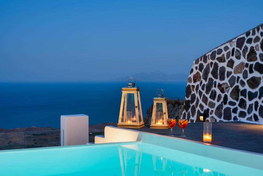 una piscina con tre candele e una vista sull'oceano di Siete Mares Luxury Suites a Imerovigli