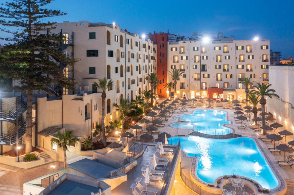 un hôtel avec une piscine, des chaises et des bâtiments dans l'établissement Hotel Hopps, à Mazara del Vallo