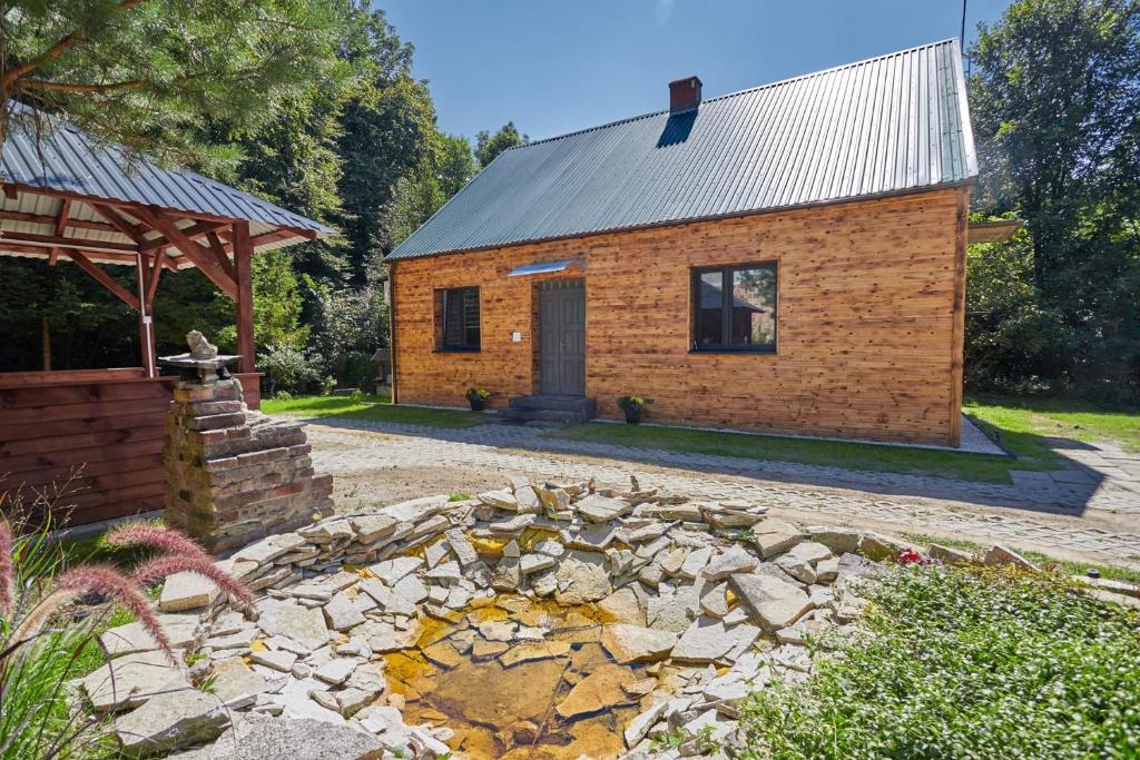 Cabaña de madera con pared de piedra y edificio en Apartamenty Domek na Roztoczu en Horyniec