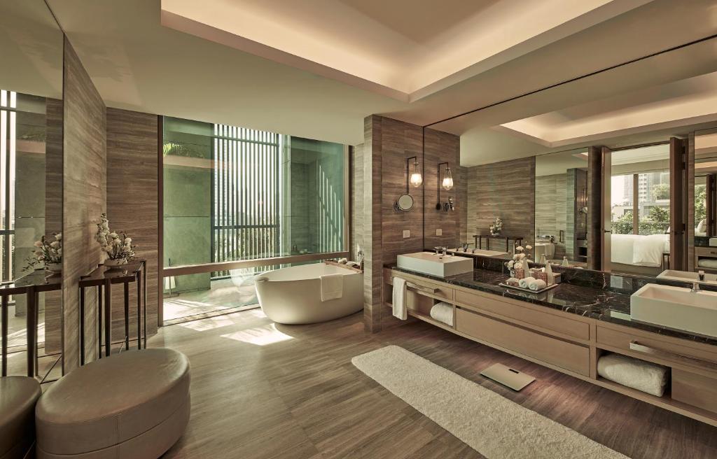 een grote badkamer met 2 wastafels en een bad bij Capella Bangkok in Bangkok