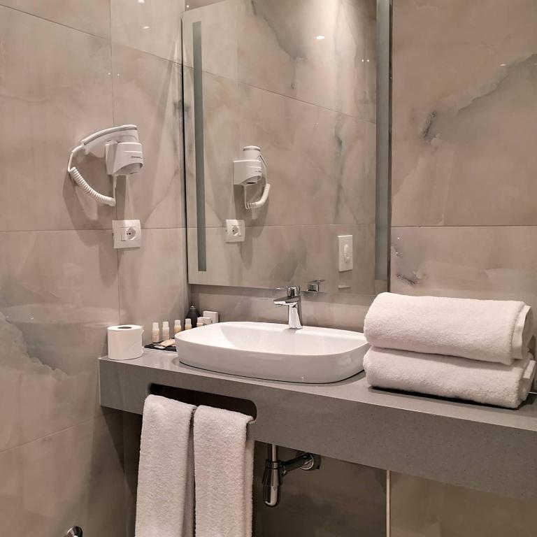 a bathroom with a sink and a mirror and towels at Iliad Hotel in Durrës