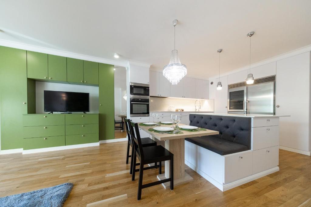 a kitchen with green cabinets and a table with chairs at Apartament Nowy Świat Centrum in Białystok