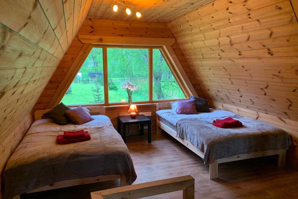 a bedroom with two beds in a log cabin at Pirtsmāja Villa Marta in Cēsis