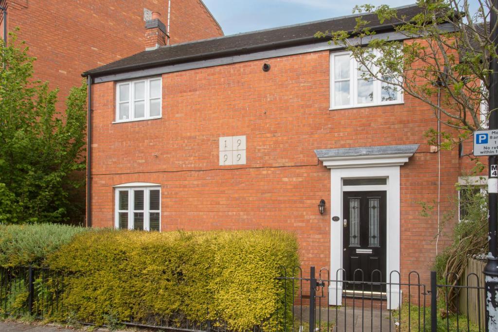 a red brick house with a black door at Rocester Roost in Rocester