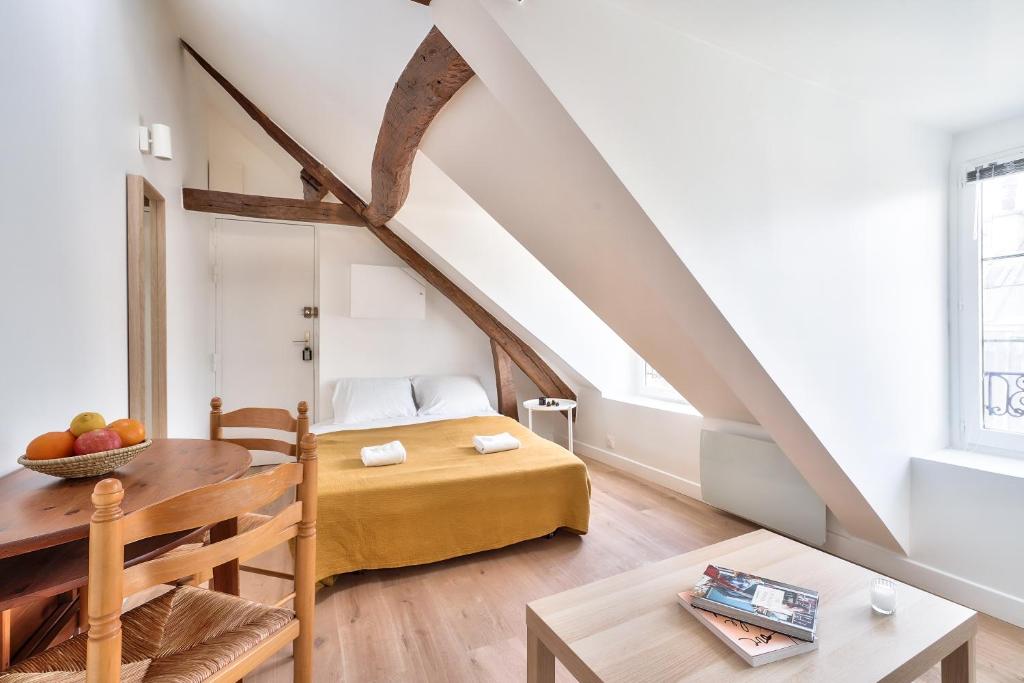 - une petite chambre mansardée avec un lit et une table dans l'établissement Charming 1 Bedroom Apt in the Heart of Paris (6F), à Paris