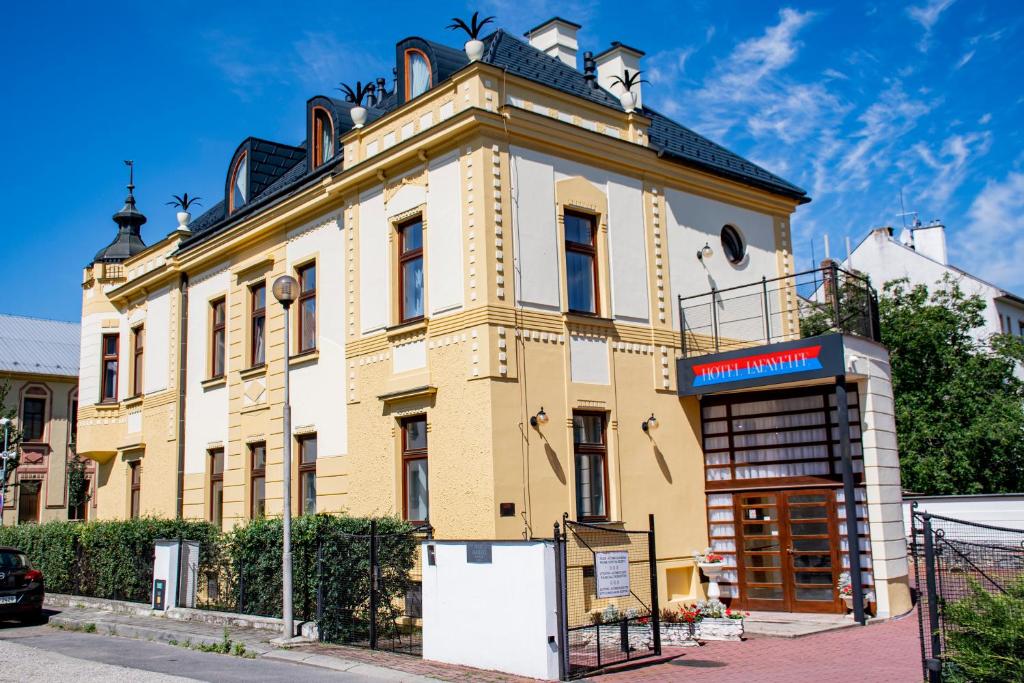 ein großes gelbes Gebäude mit einem Schild davor in der Unterkunft Lafayette in Olomouc