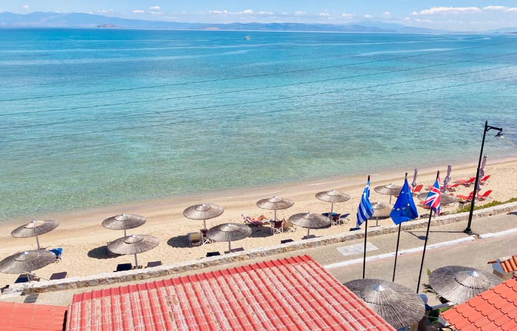 uma praia com guarda-sóis e cadeiras e o oceano em Hotel Beach Amaryllis em Megalochori