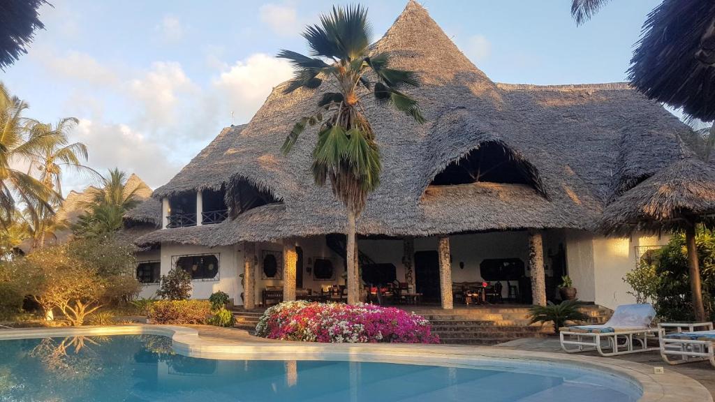 una casa con tetto di paglia e piscina di Watamu Sunrise Villa a Watamu