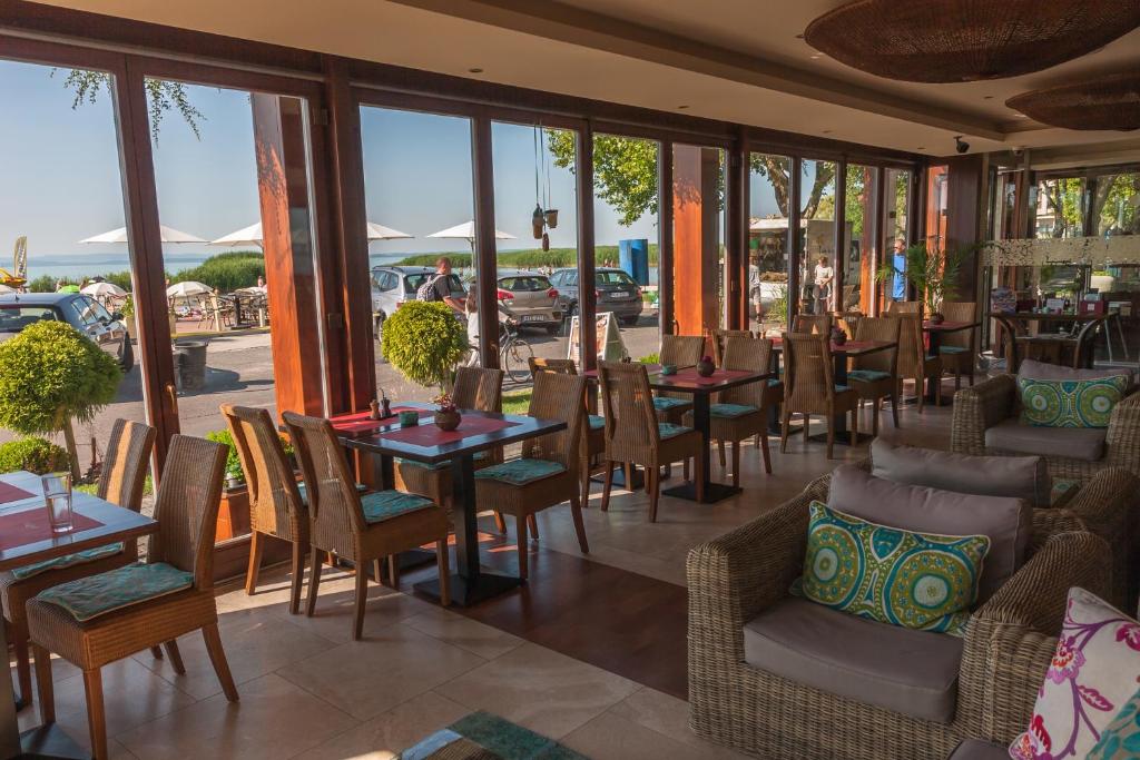 restauracja ze stołami, krzesłami i oknami w obiekcie Mala Garden Design Hotel w Siófoku