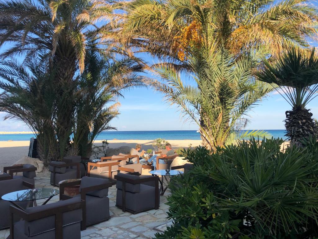 a restaurant on the beach with palm trees and the ocean at Hotel Capo San Vito by Geocharme in San Vito lo Capo