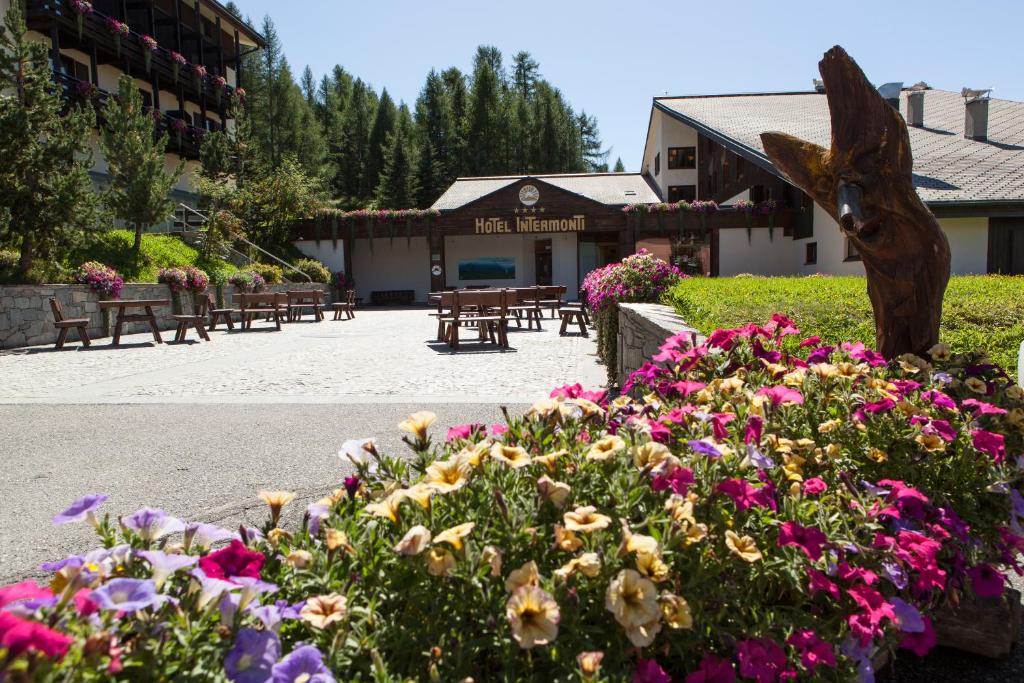 un giardino fiorito di fronte a un edificio di Hotel Intermonti a Livigno