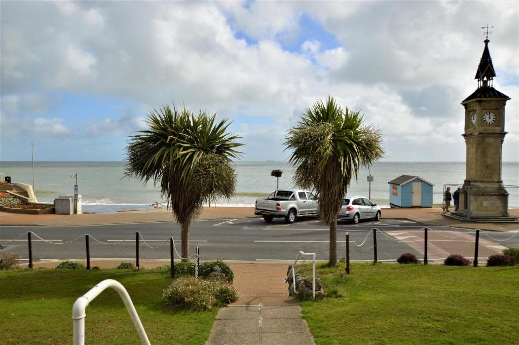 a clock tower and palm trees next to a beach at Pink Beach Holiday Apartments in Shanklin