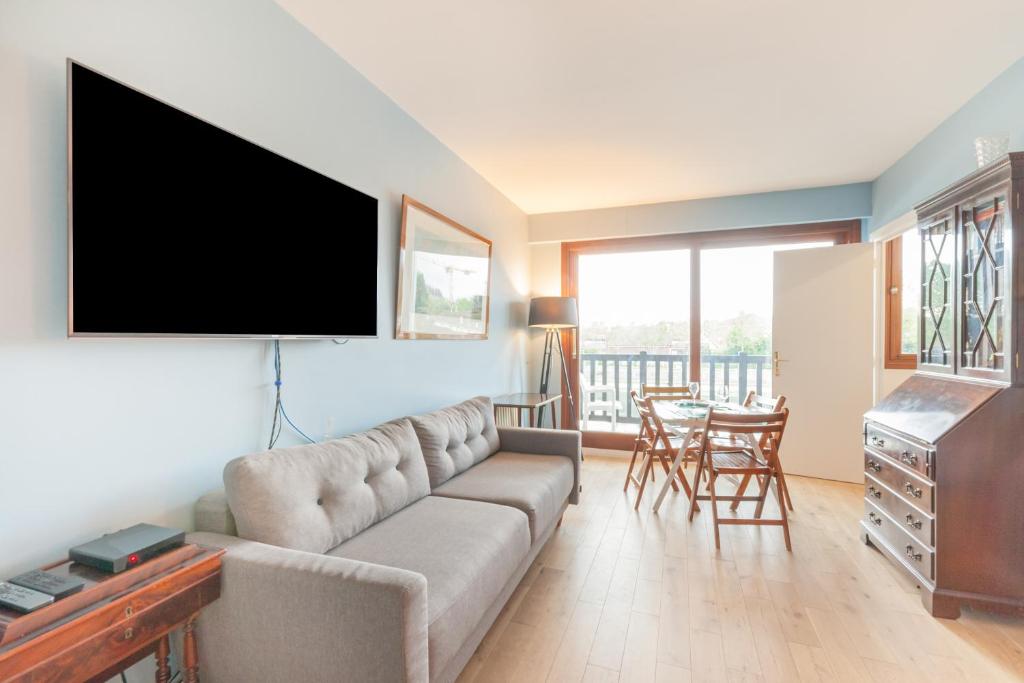 un salon avec un canapé et une télévision à écran plat dans l'établissement Le Christina, à Trouville-sur-Mer