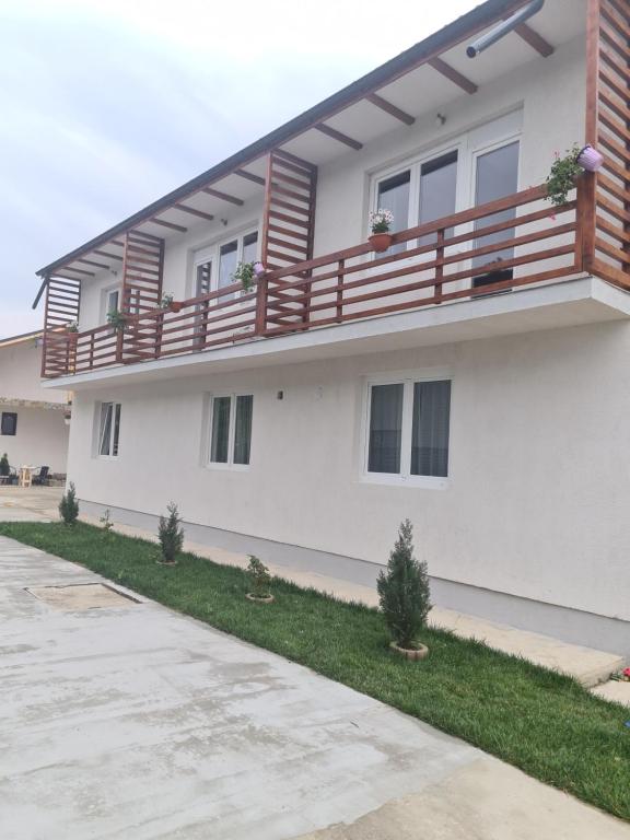 une maison blanche dotée d'un balcon en bois. dans l'établissement Luca's House ( aeroport Henry Coanda, Therme Bucuresti), à Baloteşti