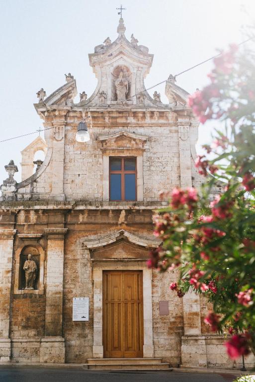 an old stone church with a wooden door and flowers at Camere Caroseno in Castellana Grotte