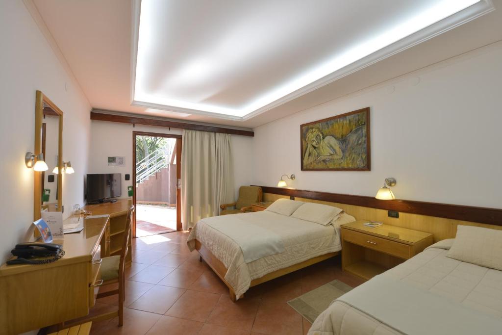 una camera d'albergo con due letti e una televisione di Hotel Restaurant Papillon a Bella Vista