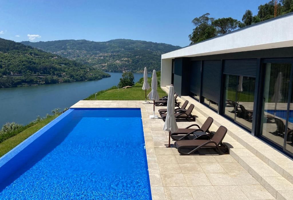 a swimming pool with chairs and a view of a river at Casa de Ribadouro in Baião