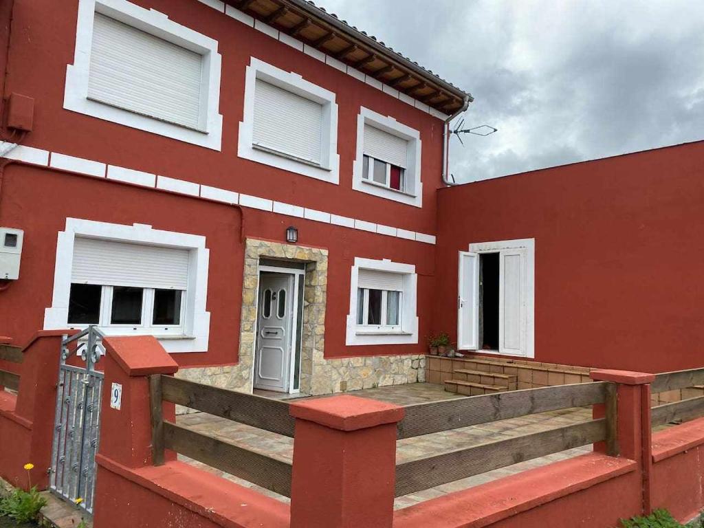 een rood huis met een houten helling ervoor bij Casa Rural Mirador de Quintana in Priesca