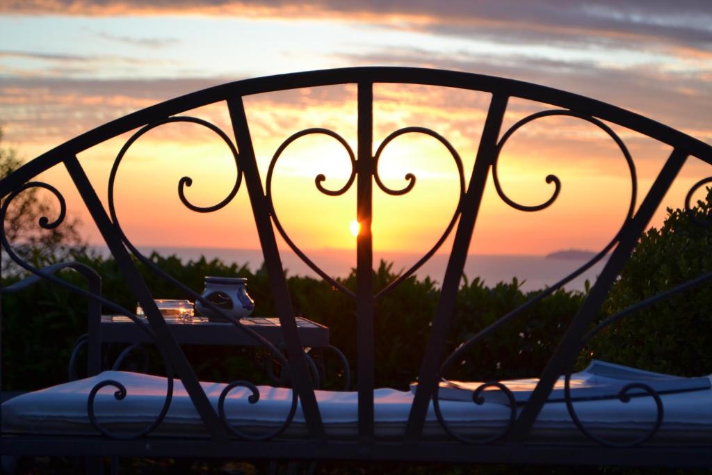 una cama de metal con una puesta de sol en el fondo en B&B The Sunset, en Anacapri